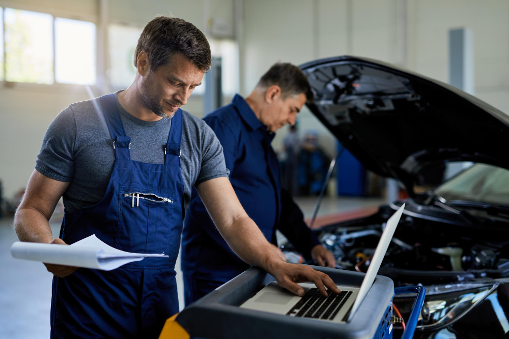 O NAMA - KDIJAGNOSTIKA obrt 2 mid adult mechanic working laptop while running car diagnostic with his coworker auto repair shop